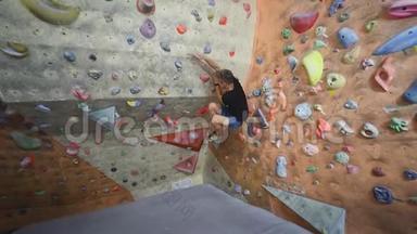 成年攀岩者正在攀岩健身房里攀岩。 男子在室内攀岩运动墙上锻炼